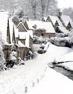 a snowy street lined with houses next to a river