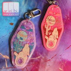 two keychains with different designs on them, one is pink and the other is blue