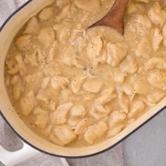 a pot filled with macaroni and cheese on top of a table next to a wooden spoon