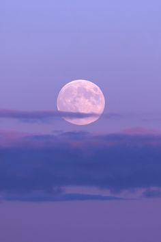 the full moon is seen through some clouds