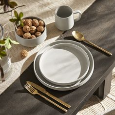 a table set with plates, silverware and gold utensils