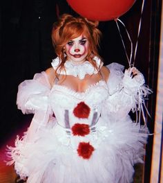 a woman dressed as a clown holding a red balloon and wearing a white dress with ruffles