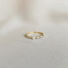 a gold ring with three small diamonds on the side, sitting on a white surface