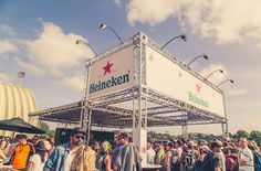 a large group of people standing around in front of a sign that says heineken