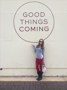 a woman standing in front of a sign that says good things coming