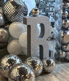 silver disco balls are sitting next to the letter b in front of a mirror ball backdrop