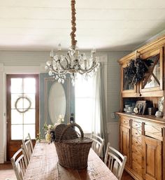 a dining room table with chairs and a basket on it's centerpiece in front of a window