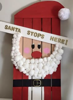 a santa clause made out of wood and cotton balls with the words santa stops here on it