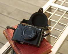 a camera sitting on top of a red book next to a metal rack with books