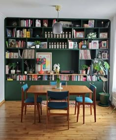 a dining room table and chairs with bookshelves in the back wall behind it