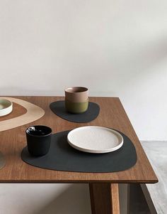 a wooden table topped with plates and cups on top of it's bases next to a white wall