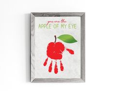 the apple of my eye is being displayed in a wooden frame with handprints on it