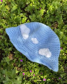 a crocheted blue hat with white hearts on it laying in some green grass