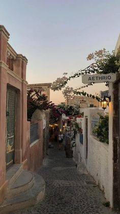 an alley way with flowers growing on the buildings and signs above it that read atetrio