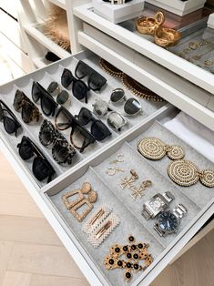 an open drawer with many pairs of sunglasses and jewelry