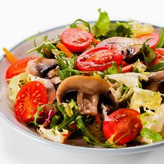 a salad with mushrooms, tomatoes and lettuce