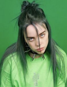 a woman with long black hair and piercings on her head wearing a green shirt