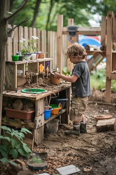 Child playing in outdoor mud kitchen with various colorful buckets and utensils in a backyard setting. Mud Kitchen Food, Kitchen For Kids, Outdoor Play Kitchen, Mud Kitchen For Kids, Mud Kitchens, Outdoor Learning Spaces, Diy Mud Kitchen