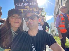 a man and woman standing next to each other in front of a sign that says sag - aftra on it