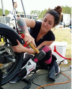 a woman is working on a motorcycle tire