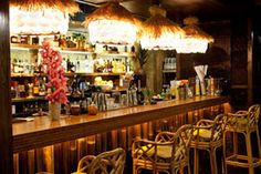 a bar with wicker chairs and lights hanging from it's ceiling above the bar