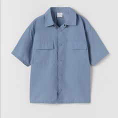 Zara Technical Nylon Shirt Blue - Size: Available In 13-14 Years In Kid's Size ( Equivalent To Size Xs In Women's) - Color: Blue - Materials: 71% Nylon, 29% Cotton. - Technical Nylon Shirt With Lapel Collar And Short Sleeves. - Front Snap Button Closure. - Front Flap Pockets. Blue Relaxed Fit Short Sleeve Shirt For Spring, Casual Blue Tops With Pockets, Zara Shirt With Pockets For Spring, Summer Zara Shirt With Pockets, Casual Blue Shirt With Pockets, Light Blue Zara Shirt For Summer, Casual Blue Collared Short Sleeve Shirt, Zara Solid Color Shirt For Summer, Zara Shirt For Summer