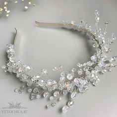 a tiara with crystal stones and pearls on the headband is laying on a table