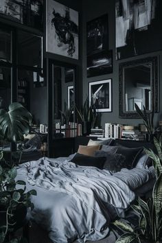 an unmade bed in a dark room with plants and pictures on the wall above it