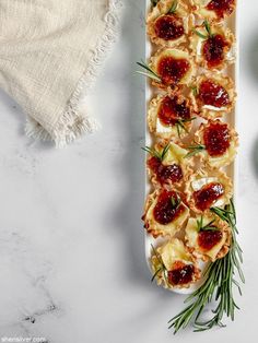 an appetizer is served on a platter with rosemary sprigs and cranberry sauce