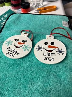 two personalized snowman ornament ornaments sitting on top of a green towel