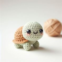 a small crocheted turtle next to a ball of yarn