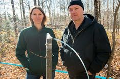 two people standing next to each other in the woods