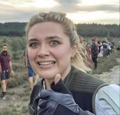 a woman is smiling while standing in front of a group of hikers on a trail