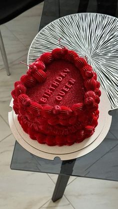 a red heart shaped cake sitting on top of a table