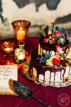 a chocolate cake with flowers on it sitting on a table next to candles and a note