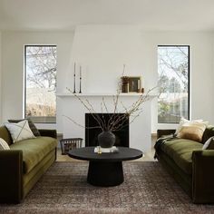 a living room with two couches and a table in front of a fire place