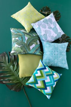 several pillows are arranged on top of each other and one has a green plant in the middle