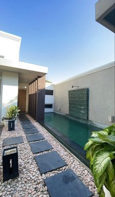 a modern house with a pool in the middle and stone walkway leading up to it