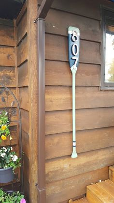 a baseball bat hanging on the side of a wooden building next to flowers and potted plants