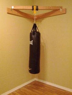 a boxing bag hanging from a wooden hanger in a room with hard wood flooring