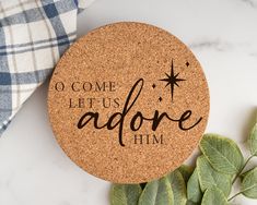 a cork coaster with the words, o come let us adore him on it