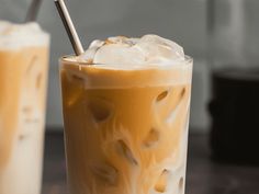 two glasses filled with iced coffee sitting on top of a table