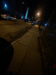 an empty street at night with cars parked on the side walk and no one in the dark