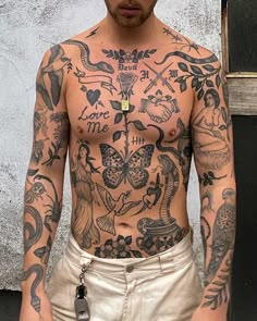 a man with lots of tattoos on his body and chest standing in front of a building