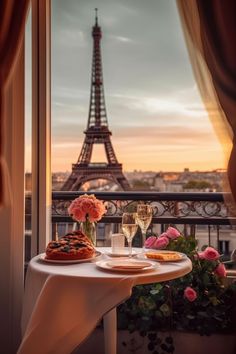 two glasses of wine are sitting on a table in front of the eiffel tower