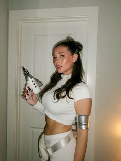 a woman in white is holding a silver object and posing for the camera with her arm wrapped around her waist