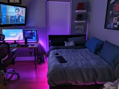 a bedroom with two computer monitors on the wall and a bed in the middle, all lit up by purple lighting