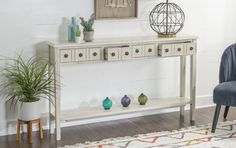 a white console table with drawers and vases