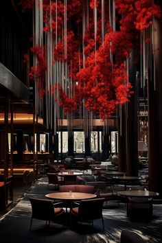 a room filled with lots of tables and chairs next to tall red flowers hanging from the ceiling