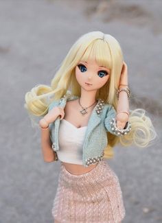 a doll with blonde hair and blue eyes wearing a white top, pink skirt and jacket